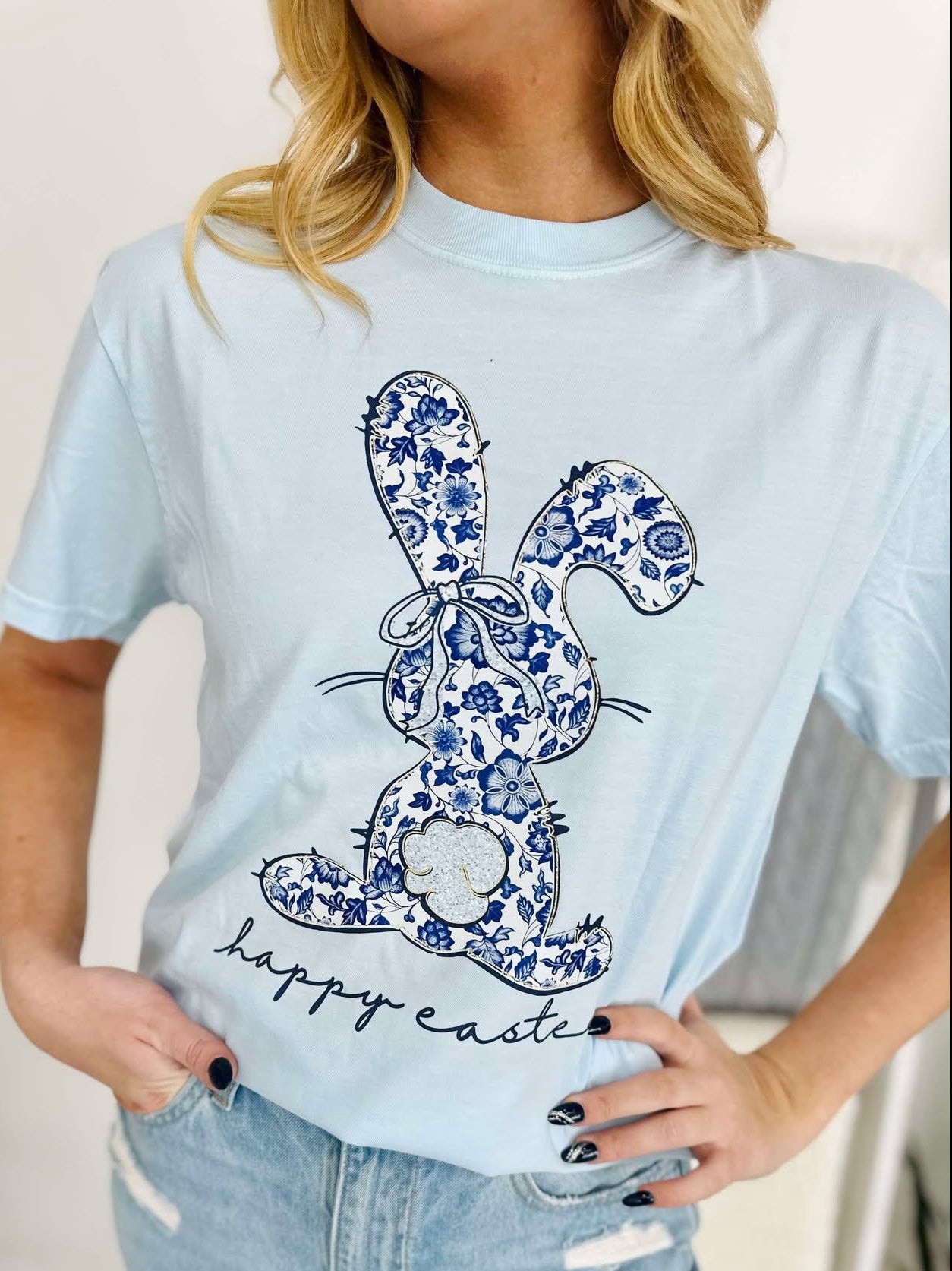 Person wearing a light blue t-shirt with a floral bunny design and 'Happy Easter' text.