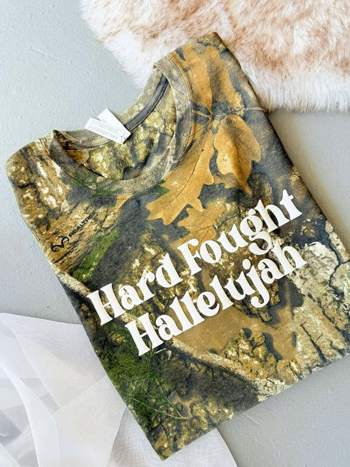 A Real Tree camouflage graphic tee with the text 'Hard Fought Hallelujah' printed in white vinyl on the front.