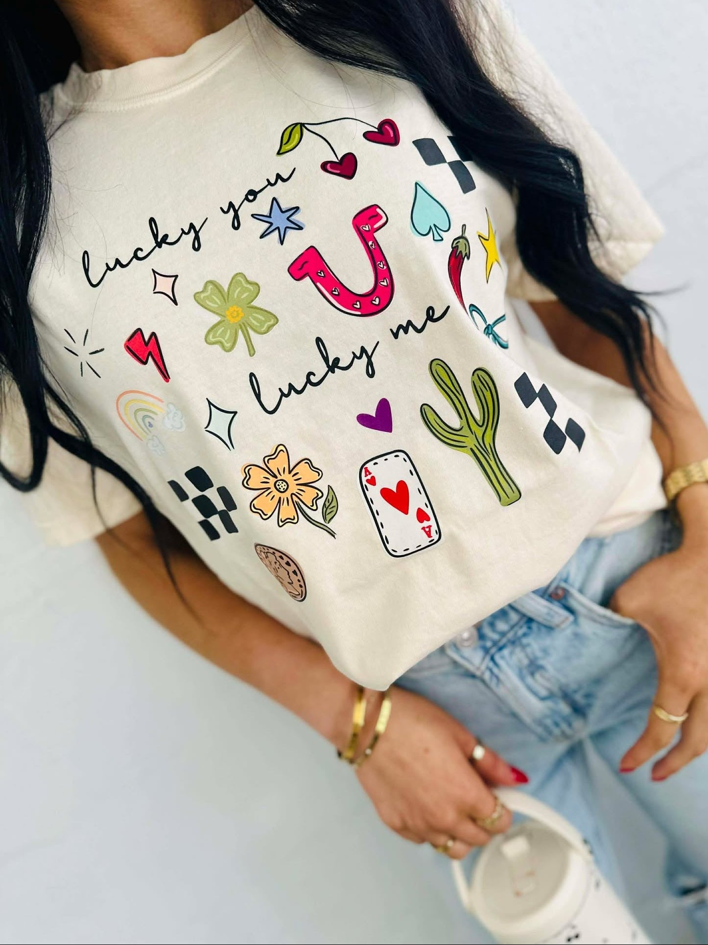 Person wearing a white t-shirt with colorful lucky you lucky me western cowboy graphics and text.