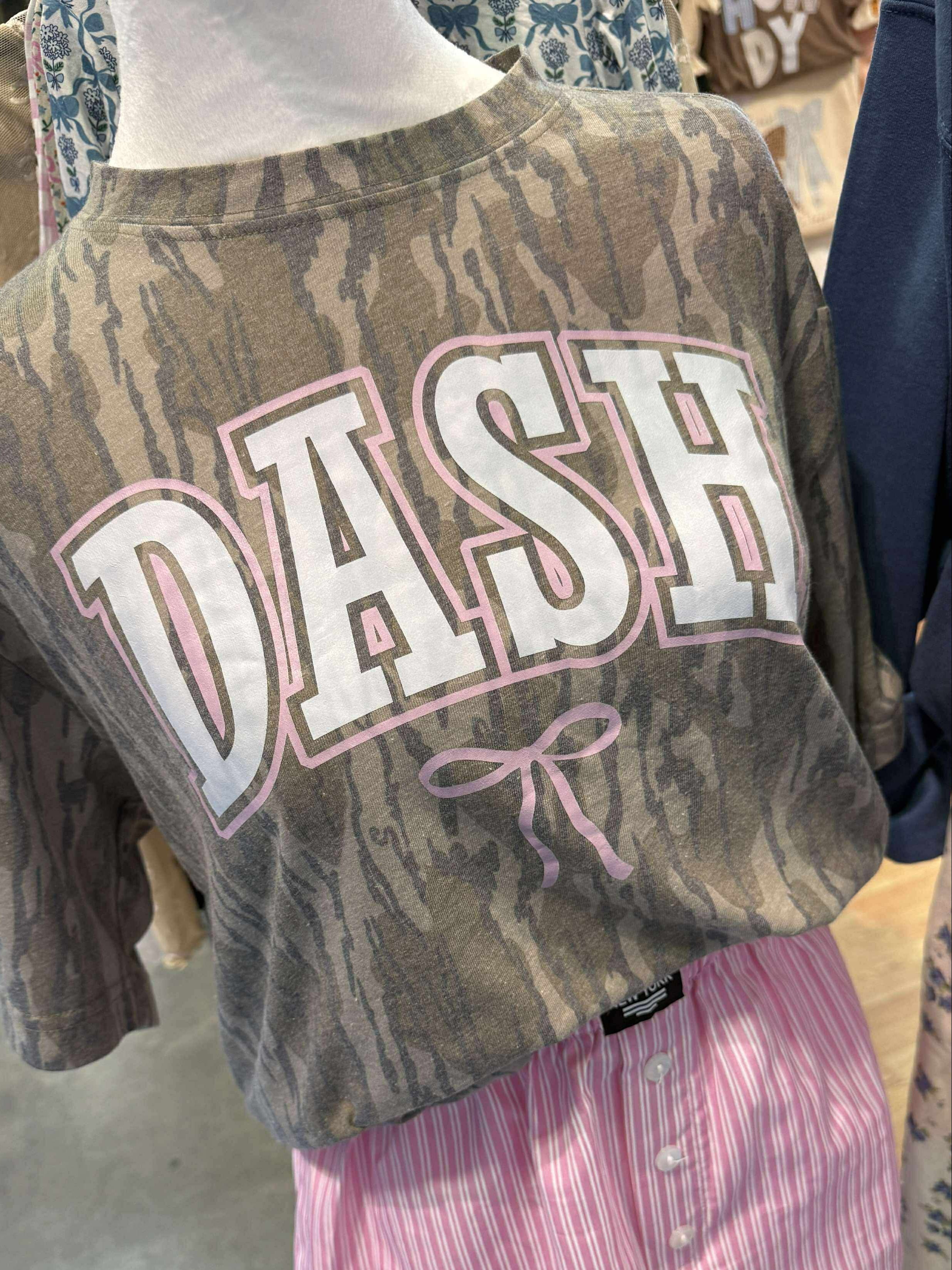 Bottomland Mossy Oak Camouflage sweatshirt with 'DASH' text and a bow on a mannequin in a store setting.