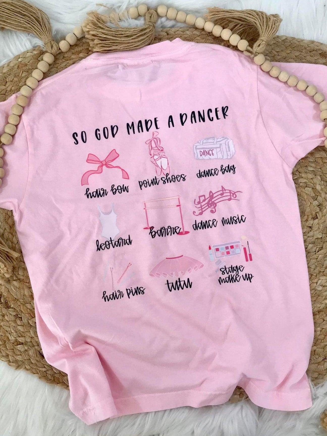 Pink t-shirt with text and graphics on a textured surface