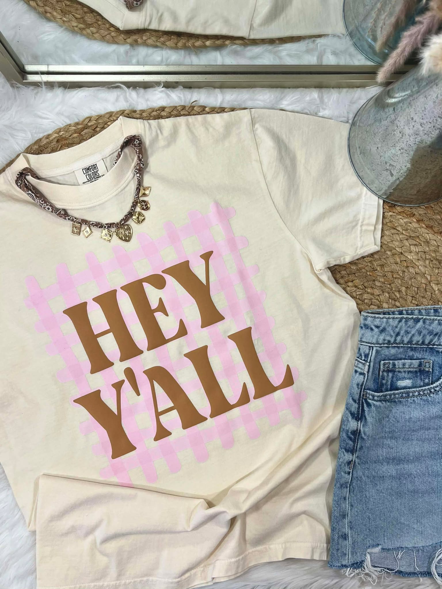 Beige t-shirt with 'HEY YALL' puff text on a dtf gingham stripes casual setting with jeans and accessories.