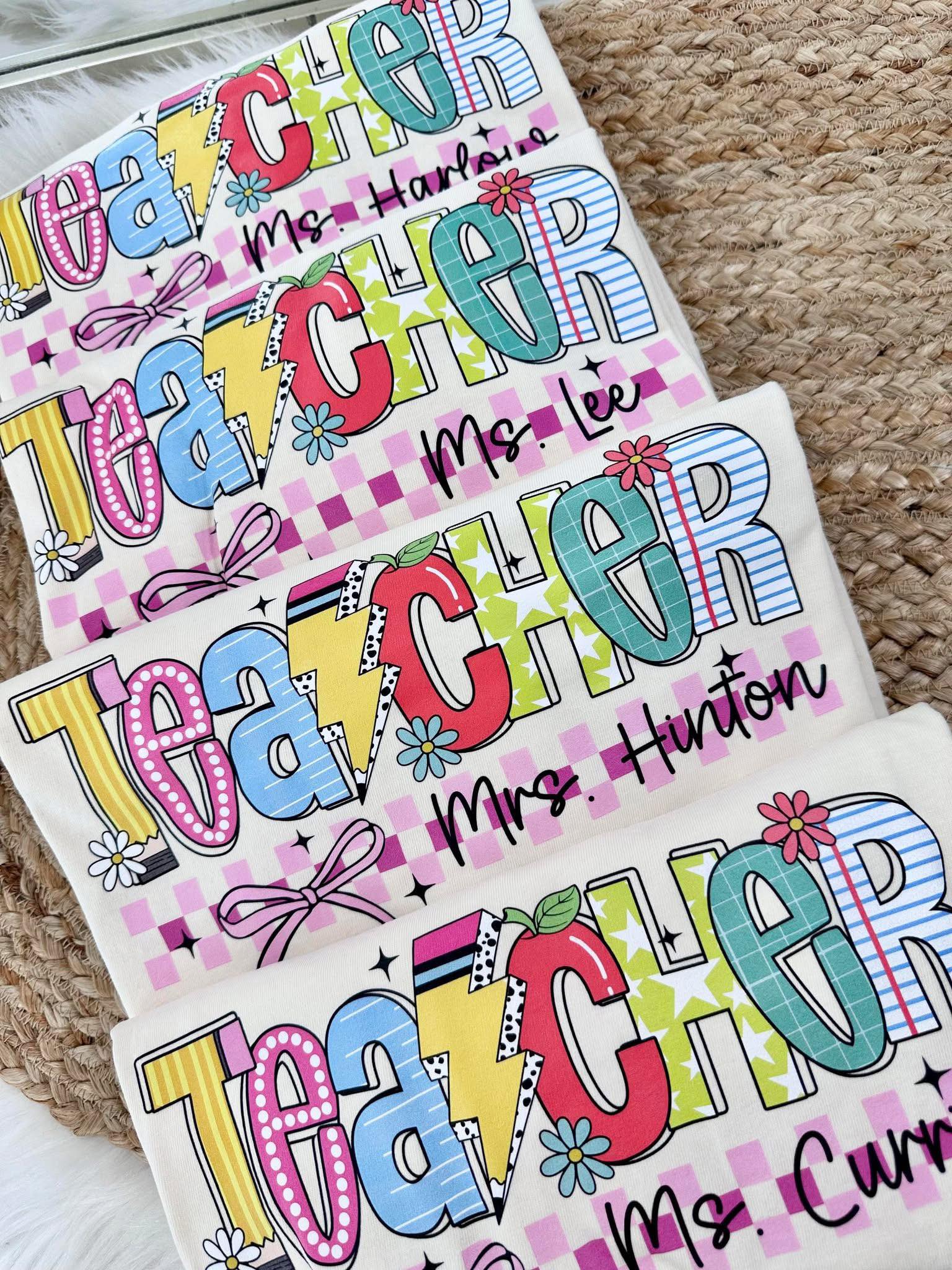 Colorful 'Teacher' nameplates with personalized text on a textured surface.