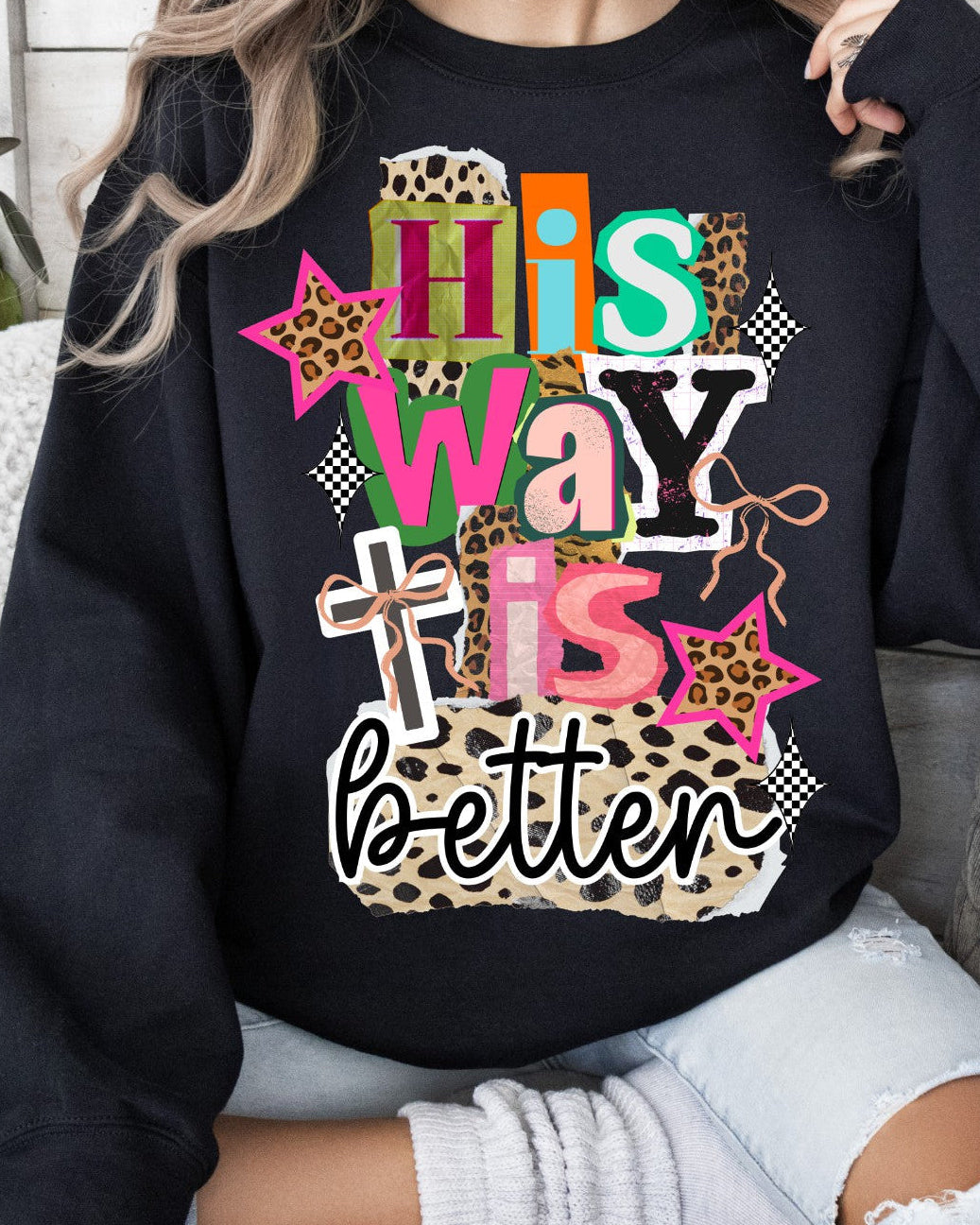 Person wearing a black sweatshirt with colorful text and patterns saying "His way is better" song lyrics
