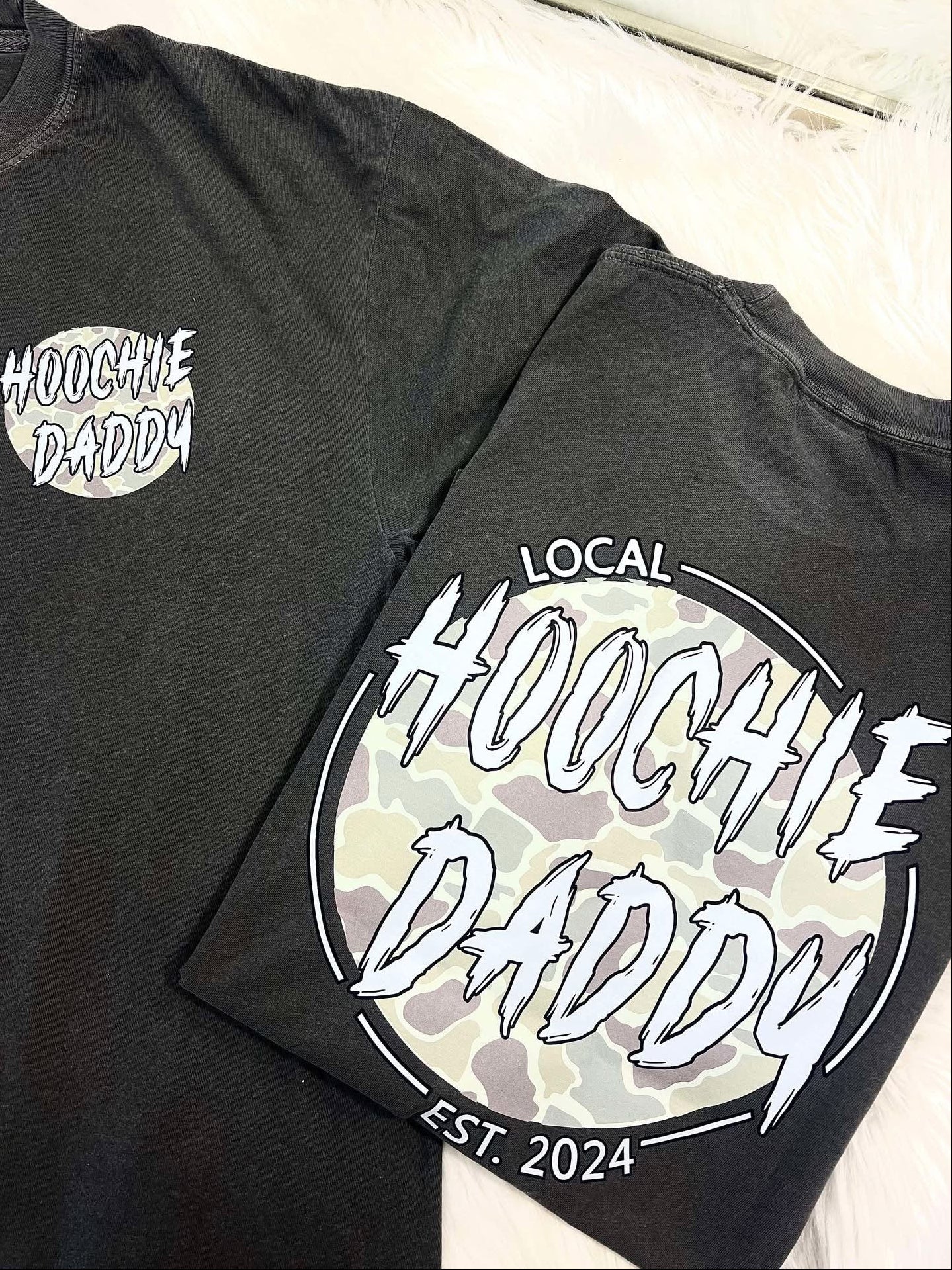Black t-shirt with 'Hoochie Daddy' branding on a wooden surface