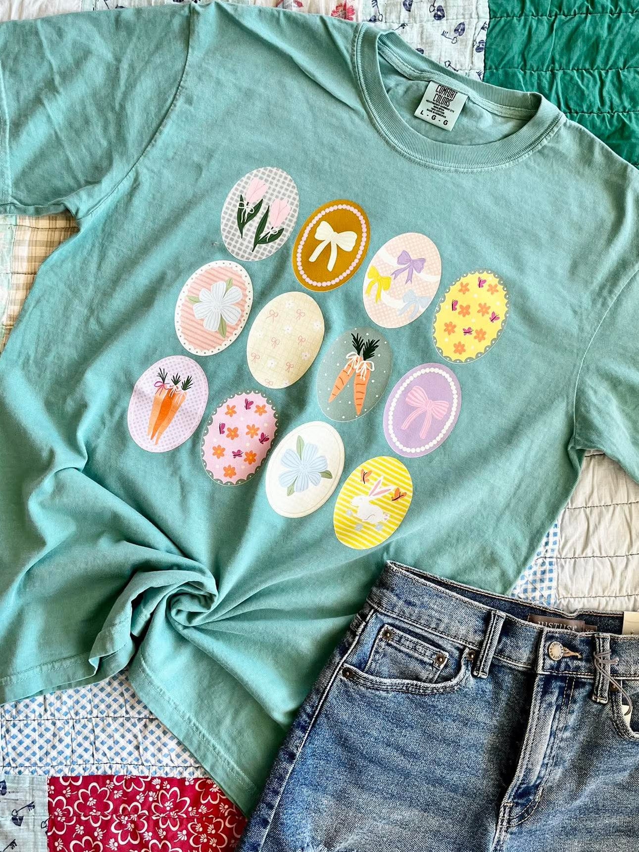 Green t-shirt with colorful designs on a patchwork quilt