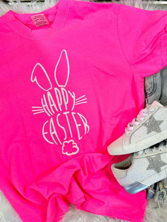 Pink t-shirt with 'Happy Easter' bunny design on a fluffy surface with sneakers.
