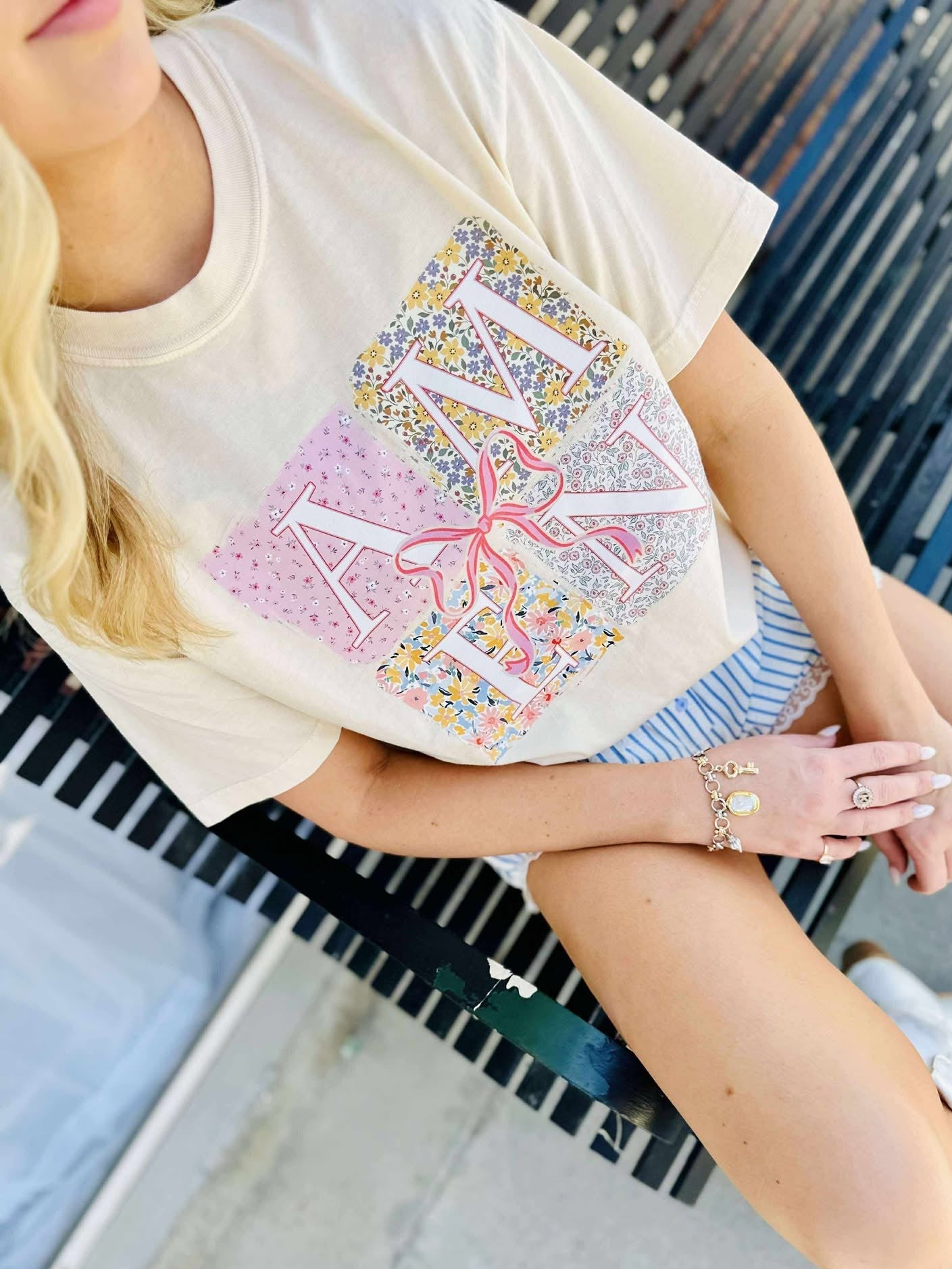Person wearing a white t-shirt with colorful  AMEN letter design sitting on a bench.