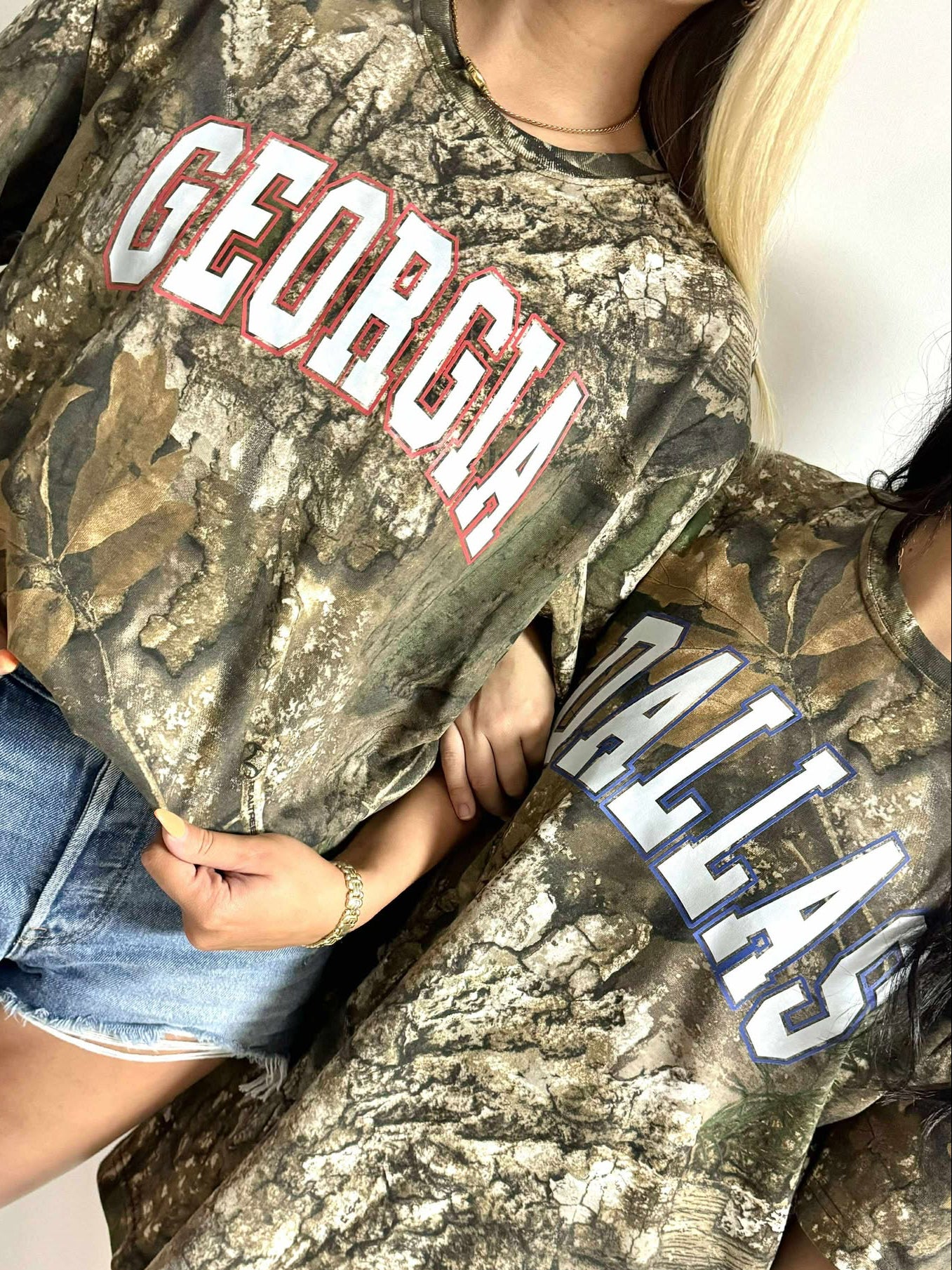 Two people wearing Real Tree camouflage t-shirts with 'Georgia' and 'Dallas' text.