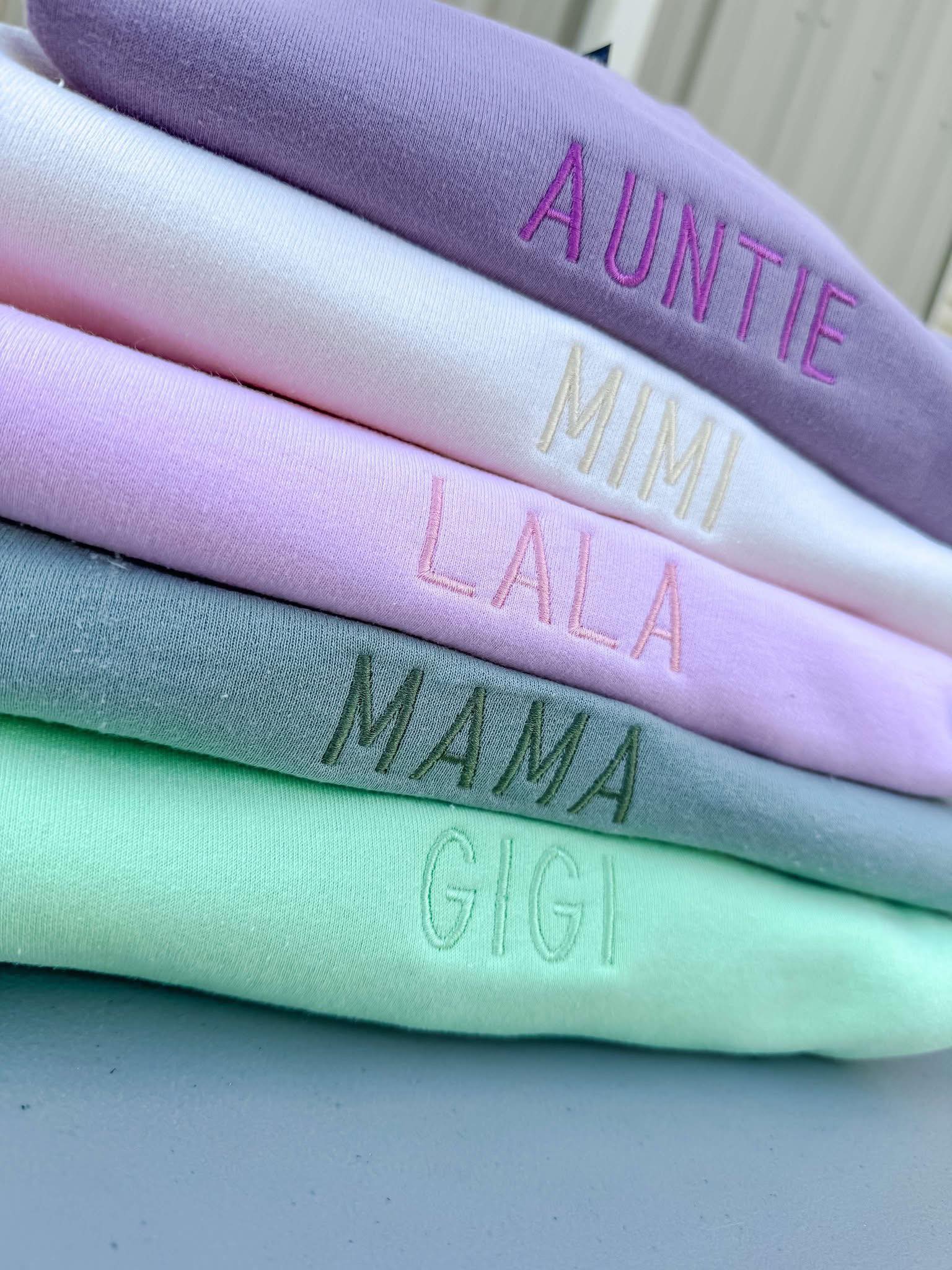 Stack of colorful fabric swatches with embroidered text on a neutral background