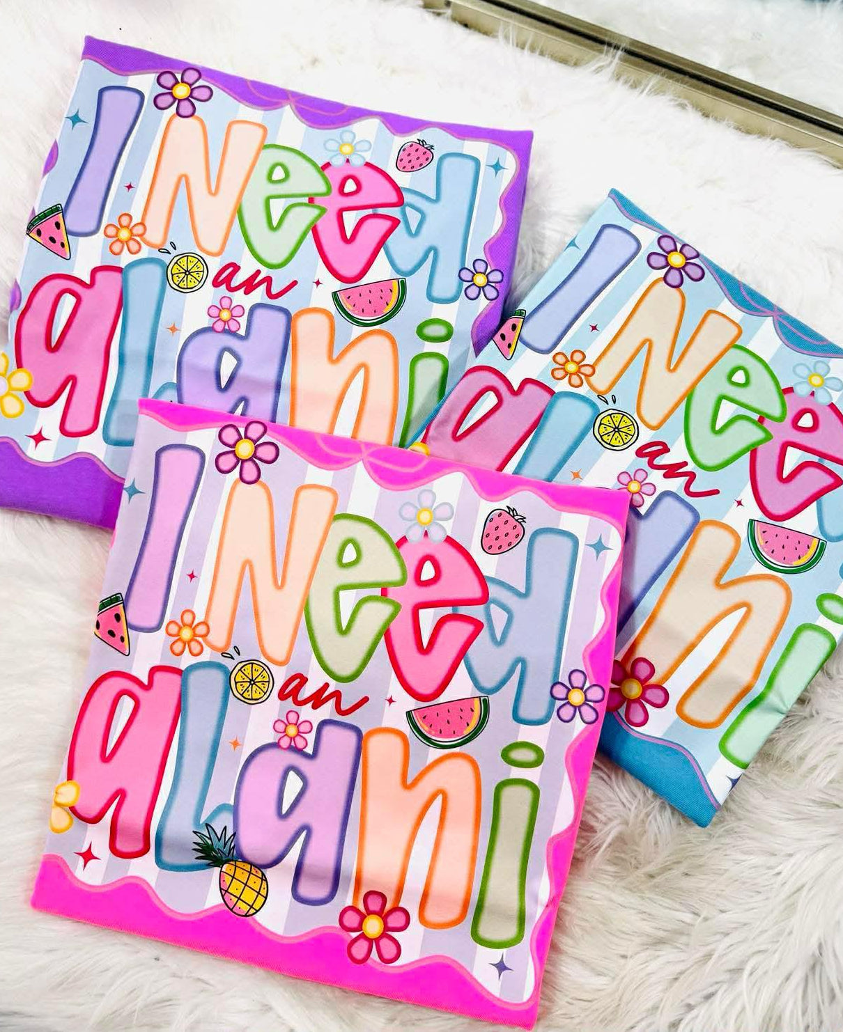 Colorful neon tee shirts with 'I need a alani' multi color dtf on a white surface