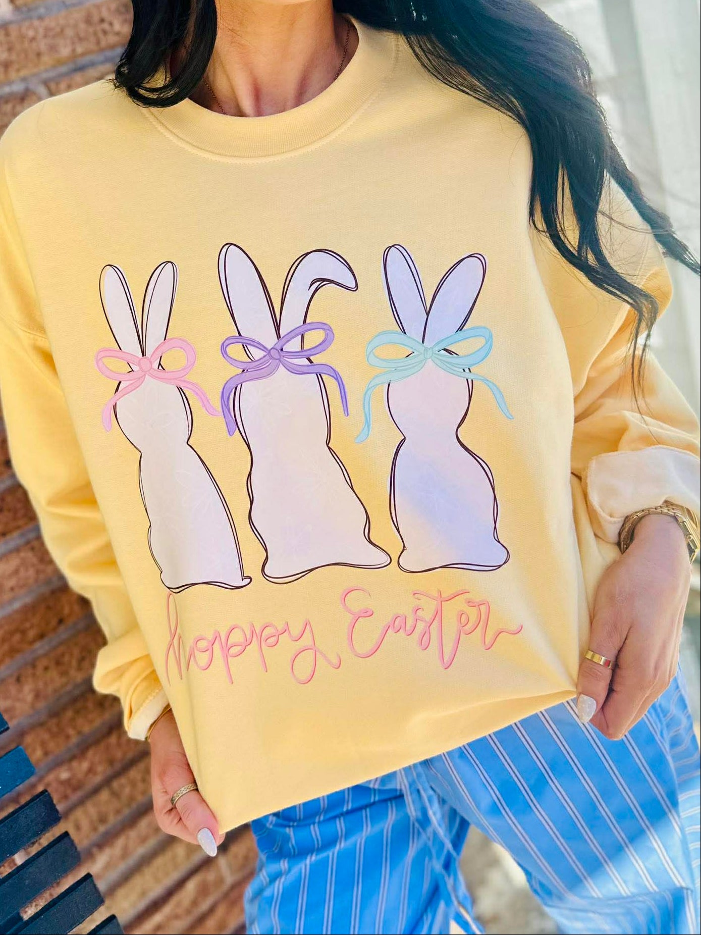 Person wearing a yellow sweatshirt with Easter bunny Hoppy Easter graphics and text.