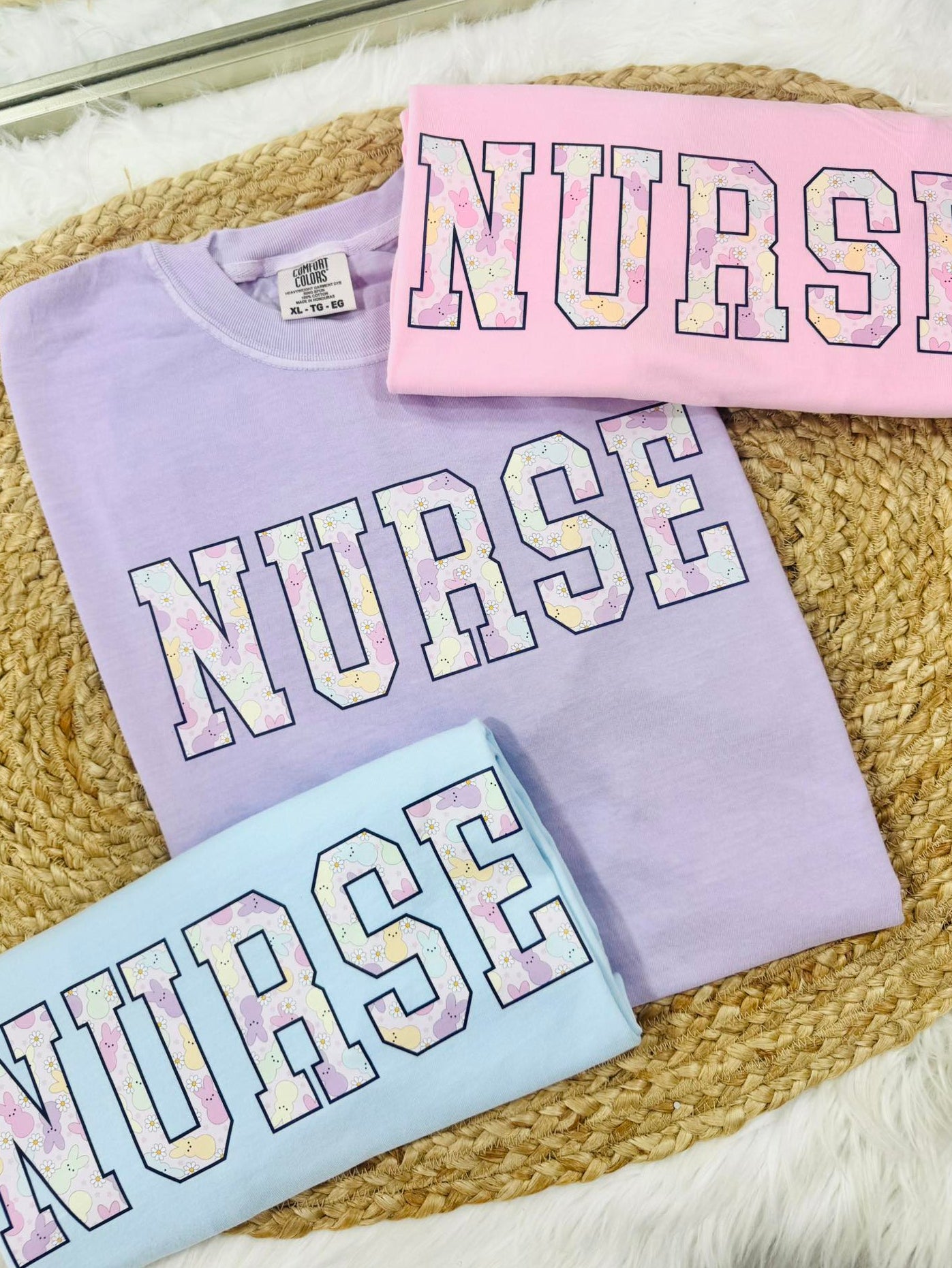 Three sweatshirts with 'NURSE' text in pastel colors with Peeps on a textured surface.