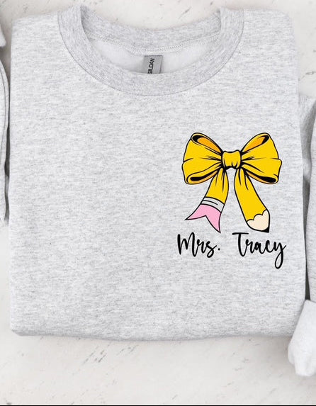 Gray sweatshirt with a yellow pencil bow and 'Mrs. Tracy' dtf graphic text on a white background